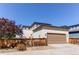 Tan house with brown garage and rustic wooden fence and a red tree providing shade at 10152 Southlawn Cir, Commerce City, CO 80022