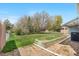 Backyard with large lawn, trees, and retaining wall at 835 S Geneva St, Aurora, CO 80247