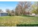Spacious backyard with a large lawn and various trees and bushes, warning sign at 835 S Geneva St, Aurora, CO 80247