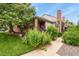 Charming home exterior with brick accents, a red door, mature trees and beautiful landscaping at 4231 S Fairplay Cir # A, Aurora, CO 80014