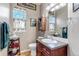 Traditional half bathroom featuring dark wood vanity, white sink, and window with floral curtains at 3545 Cottonwood Cir, Longmont, CO 80504