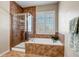 Elegant bathroom featuring a walk in shower and bathtub with stone tile and a window at 3545 Cottonwood Cir, Longmont, CO 80504