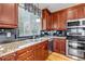 Kitchen area features granite countertops, cherry cabinets, tiled backsplash, and stainless steel appliances at 3545 Cottonwood Cir, Longmont, CO 80504