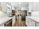Modern kitchen featuring white cabinets, stainless steel appliances, and sleek countertops with view to the living room at 8736 W 46Th Ave, Wheat Ridge, CO 80033