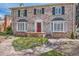 Charming brick home with red door, bay windows, landscaped yard, and a stone walkway leading to the front entrance at 1000 N Monaco Pkwy, Denver, CO 80220