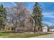 Charming brick home with mature trees, a retaining wall, a well-manicured lawn, and a detached garage at 1000 N Monaco Pkwy, Denver, CO 80220