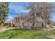 Charming brick home with mature trees, a retaining wall, and a well-manicured lawn at 1000 N Monaco Pkwy, Denver, CO 80220