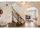 Inviting foyer with hardwood floors, a staircase with white spindles, and an arched doorway leading to the dining room at 1000 N Monaco Pkwy, Denver, CO 80220
