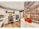 Updated kitchen features stainless steel appliances, white cabinets, brick accent wall, and ample counter space for cooking at 1000 N Monaco Pkwy, Denver, CO 80220
