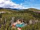 Breathtaking aerial view of a mountain home surrounded by a lush green forest with mountain views in the distance at 9123 Booker Ln, Conifer, CO 80433