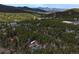 Expansive aerial view of a home nestled amongst dense trees with mountain views in the distance at 9123 Booker Ln, Conifer, CO 80433
