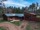 Rustic brown home featuring a green metal roof, front patio, and detached garage surrounded by dense trees at 9123 Booker Ln, Conifer, CO 80433