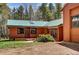 Exterior view featuring wood siding, a durable green metal roof, and lush landscaping at 9123 Booker Ln, Conifer, CO 80433