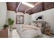 A staged main bedroom with exposed beam and view to winter landscape at 9123 Booker Ln, Conifer, CO 80433