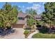 Charming two-story home featuring a brick facade, attached garage, and beautifully landscaped front yard with mature trees at 5373 E Links Cir, Centennial, CO 80122