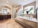 Luxurious bathroom featuring a soaking tub, a glass block shower, tile floors, and dual vanities at 6561 Ocaso Dr, Castle Pines, CO 80108