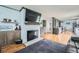 Open-concept living space with hardwood floors, a white brick fireplace and access to the kitchen at 8007 S Dover St, Littleton, CO 80128