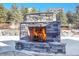 Outdoor stone fireplace burning in snowy backyard at 359 Castlemaine Ct, Castle Rock, CO 80104