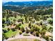 Expansive aerial view showcases the home's location nestled within a lush, mountainous, wooded landscape at 21868 Mountsfield Dr, Golden, CO 80401