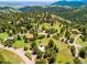 Wide aerial shot reveals the property nestled in a wooded, rolling landscape with mountain views at 21868 Mountsfield Dr, Golden, CO 80401
