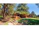 Expansive backyard featuring a hot tub, patio, trees, and lush greenery, perfect for outdoor living at 21868 Mountsfield Dr, Golden, CO 80401