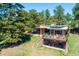Aerial view of a brick home with a deck, hot tub, and patio surrounded by lush greenery at 21868 Mountsfield Dr, Golden, CO 80401
