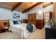 Well-lit bedroom featuring exposed beams, wood paneling, and neutral decor at 21868 Mountsfield Dr, Golden, CO 80401
