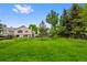 Expansive backyard with lush green lawn, mature trees, and partial fencing, offering privacy at 18 Blue Sage, Littleton, CO 80127