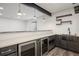 Finished basement bar with stainless steel beverage coolers, a farmhouse sink, shelving, and modern lighting at 6405 Kenzie Cir, Castle Pines, CO 80108