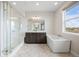 Bright, modern bathroom features a glass-enclosed shower, soaking tub, and double vanity with beautiful countertops at 6405 Kenzie Cir, Castle Pines, CO 80108