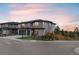 Two-story home with gray siding, a well-manicured lawn, and a spacious driveway, set against a beautiful sunset backdrop at 6405 Kenzie Cir, Castle Pines, CO 80108