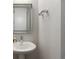 Modern powder room with a pedestal sink, illuminated mirror, and sleek fixtures in a minimalist design at 6405 Kenzie Cir, Castle Pines, CO 80108