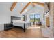 Spacious bedroom with wood beam ceiling, hardwood floors, a stone fireplace, and large picture windows at 7868 Cicero Ct, Littleton, CO 80125