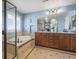 Main bathroom featuring double vanity, large mirror, soaking tub, and walk-in shower with blue wall paint at 7680 S Blackstone Pkwy, Aurora, CO 80016