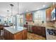 Spacious kitchen features wood floors, granite counters, stainless steel appliances, and modern pendant lighting at 7680 S Blackstone Pkwy, Aurora, CO 80016