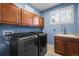 Functional laundry room with sink, storage cabinets, a window with shutters, and modern washer and dryer at 7680 S Blackstone Pkwy, Aurora, CO 80016