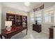Well-lit office with a dark wood desk, built-in bookshelves, tile floors, and plantation shutters at 7680 S Blackstone Pkwy, Aurora, CO 80016