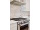 Close up of the kitchen stove, featuring a herringbone backsplash and stainless hood at 1836 Grove St # 108, Denver, CO 80204