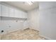 Functional laundry room featuring tile floors, a utility sink, and ample cabinet space at 10155 Charissglen Ln, Littleton, CO 80126
