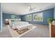 Spacious main bedroom with serene blue walls, plush carpet, and a cozy seating area by the windows at 10155 Charissglen Ln, Littleton, CO 80126