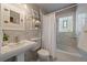 Elegant bathroom with marble walls, a pedestal sink, and a tub/shower with glass block window at 1840 S Grant St, Denver, CO 80210