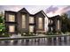 Stunning new build townhome with a modern farmhouse aesthetic, professional landscaping, and inviting exterior lighting at 6872 Huddersfield Ln, Castle Pines, CO 80108