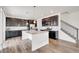 Spacious kitchen featuring stainless steel appliances, a granite island, dark cabinets, and staircase access at 12777 Clearview St, Firestone, CO 80504
