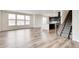Open-concept living room featuring wood floors, large windows, and a modern kitchen view with dark cabinets at 12777 Clearview St, Firestone, CO 80504