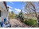 A spacious wooden deck with black railing and wicker seating overlooks lush greenery at 7888 S Magnolia Way, Centennial, CO 80112