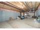 Unfinished basement with exposed wooden ceiling beams, concrete walls, and plywood flooring, offering potential for customization at 6092 S Ouray St, Aurora, CO 80016