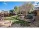 Beautifully landscaped backyard with a lush lawn, decorative retaining wall, and mature trees at 10359 Tracewood Dr, Highlands Ranch, CO 80130