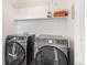 Modern laundry room with front-loading Samsung washer and dryer, and convenient upper shelf at 10359 Tracewood Dr, Highlands Ranch, CO 80130