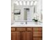 Bright bathroom featuring a wood vanity with a white countertop, decorative mirror, and fresh white flower decor at 212 Mulligan Lake Dr, Mead, CO 80542