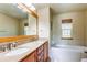 Bathroom featuring double sinks, granite countertops, a large mirror, and a tub with white tile surround at 3354 Wabash St, Denver, CO 80238